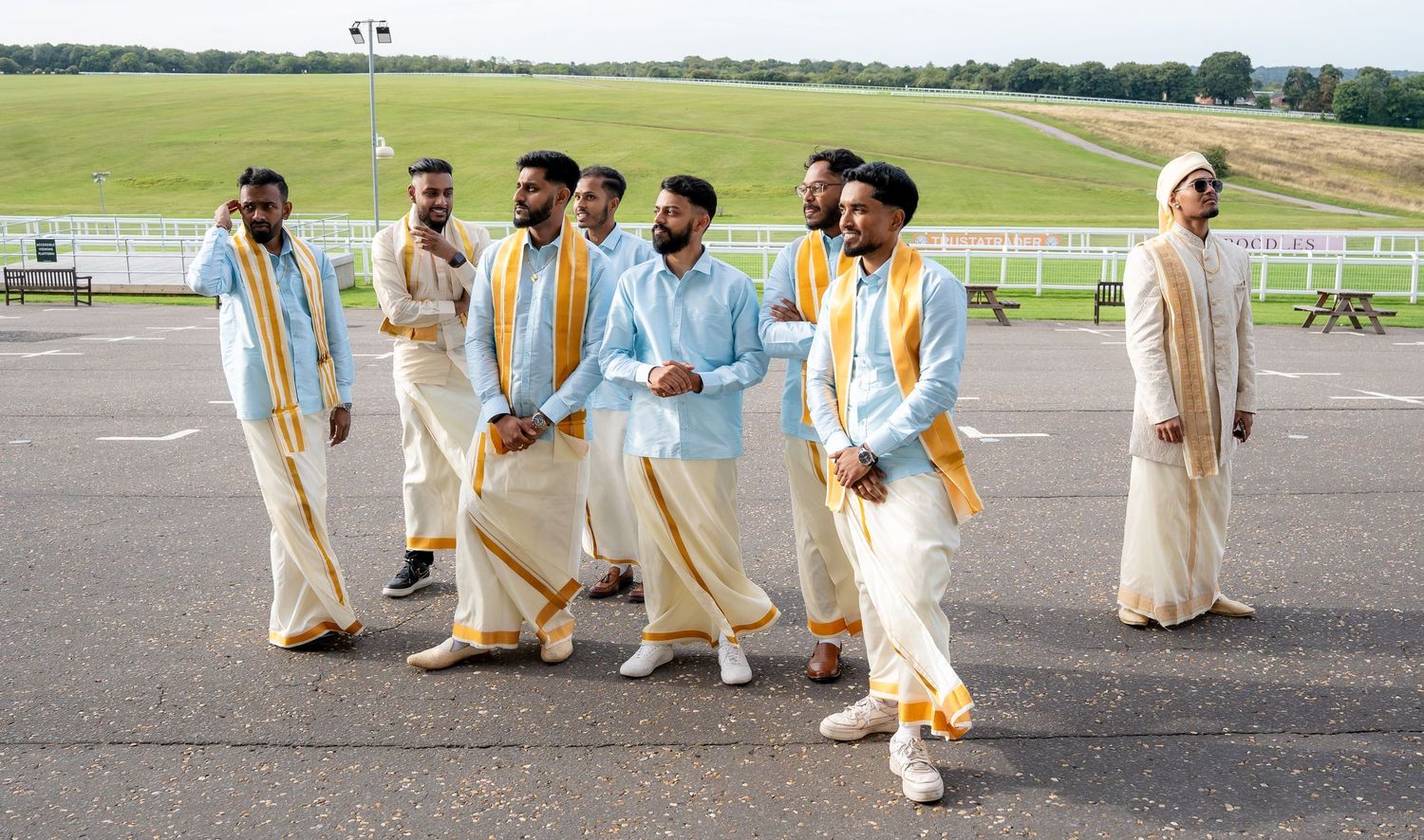 Group of men in light blue and white traditional South Asian attire walking outdoors.