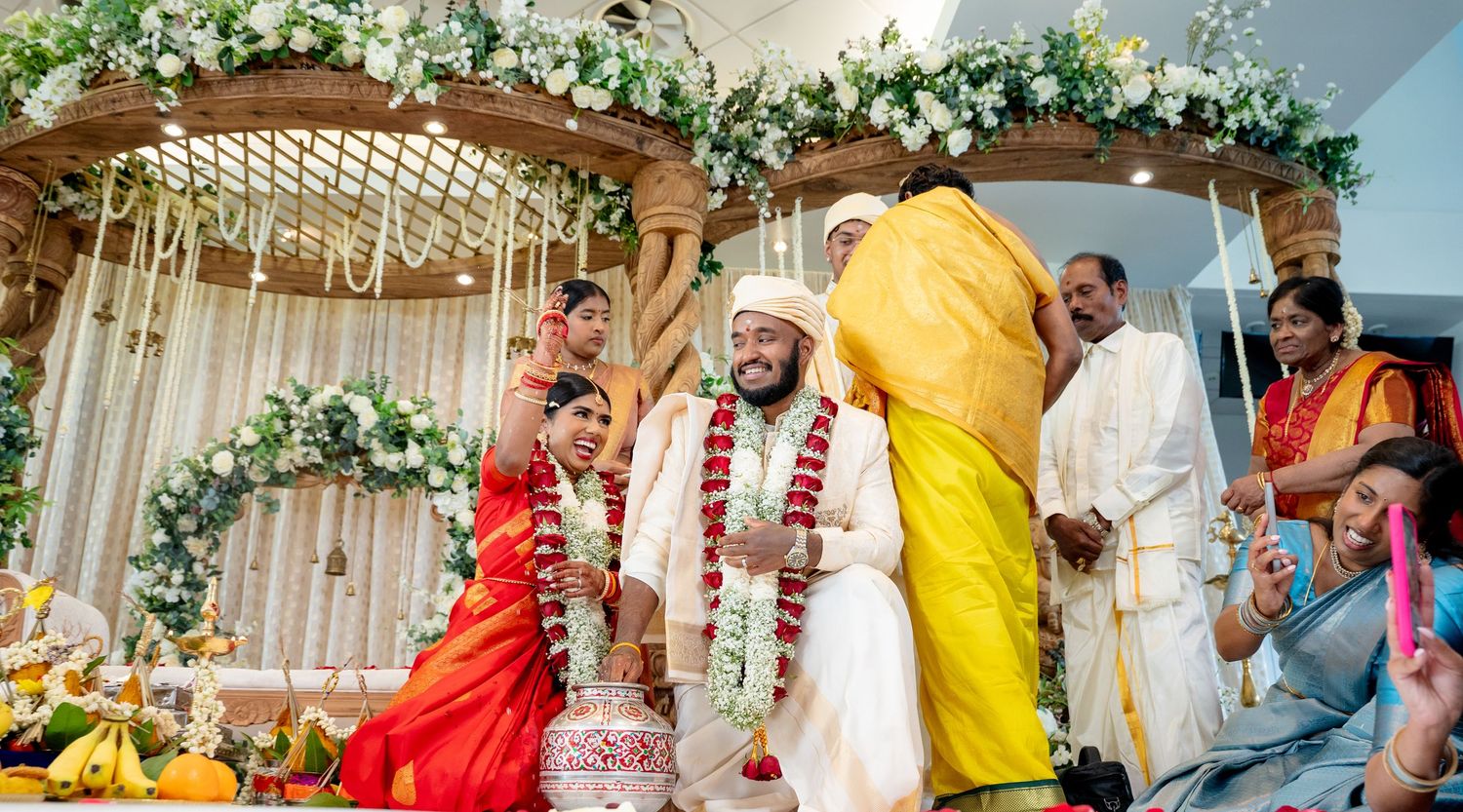 Bride and groom share a cheerful moment during a vibrant traditional South Indian Hindu wedding ceremony.
