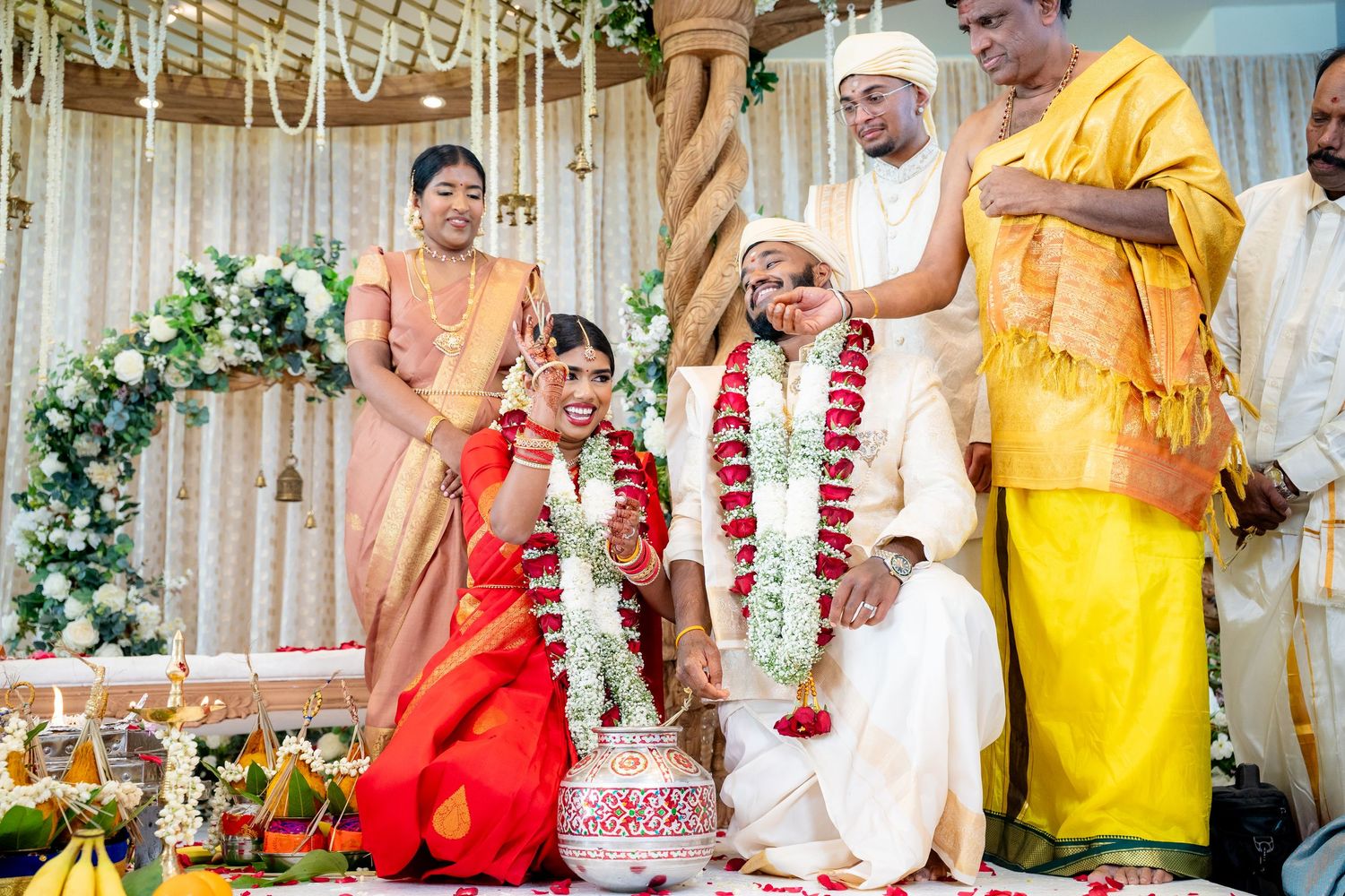 Bride and groom exchange garlands during a traditional South Indian Hindu wedding ceremony on a decorated mandap.