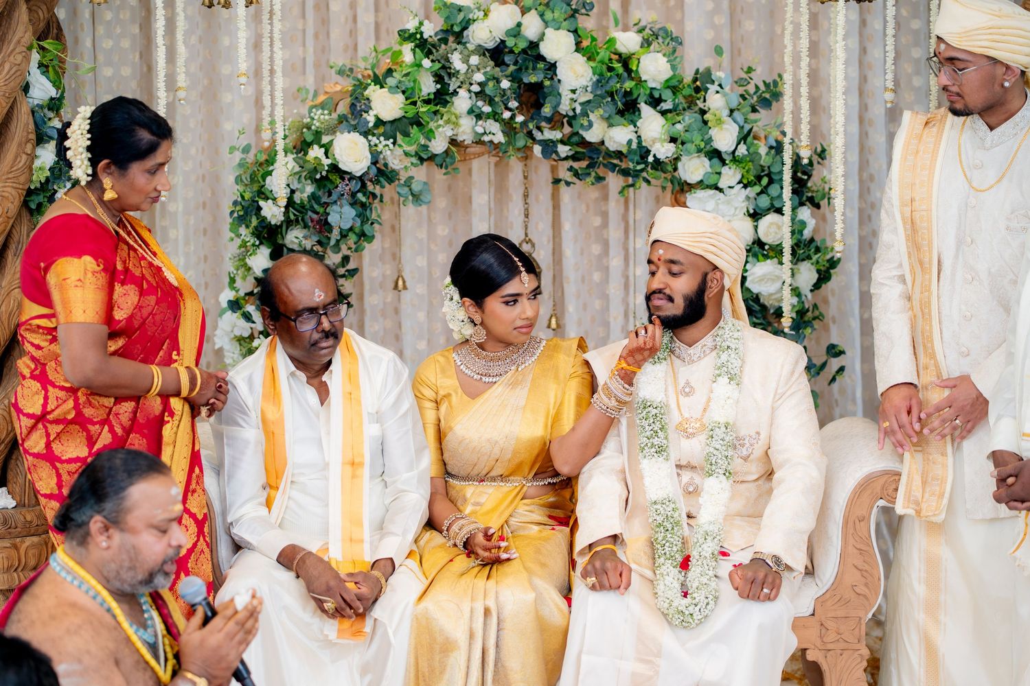 Hindu wedding ceremony with bride in gold silk saree and groom in embroidered sherwani at decorated mandap.