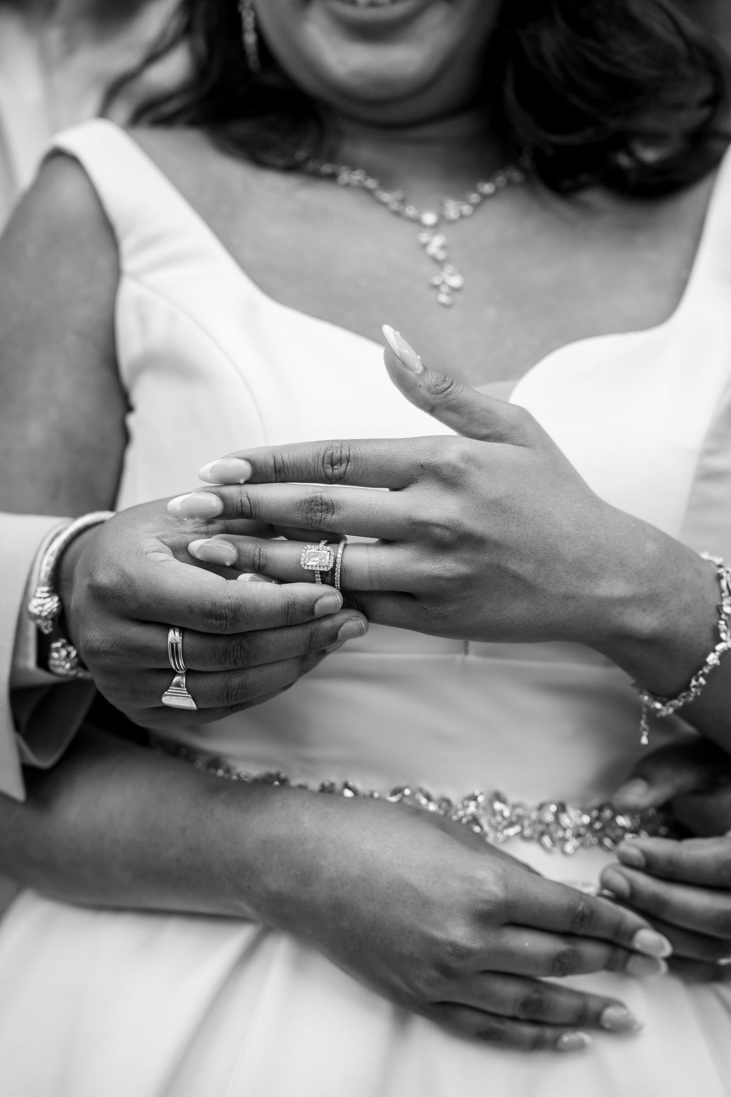 Black and white photo of a groom placing a wedding ring on his bride's finger during their ceremony.