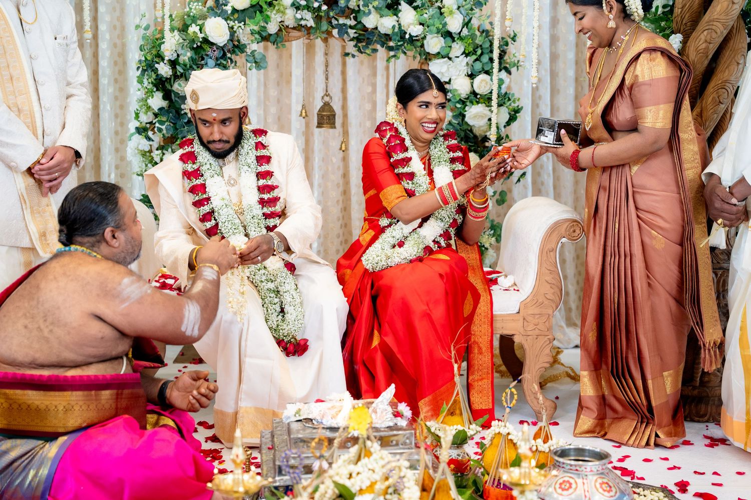 Bride and groom perform sacred Hindu wedding rituals with priest and traditional ceremonial items.