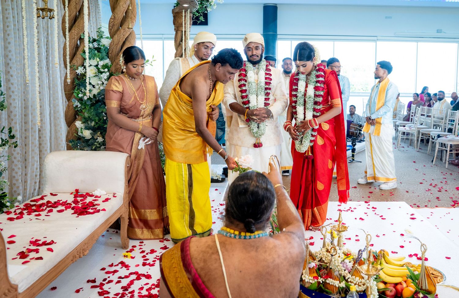 Hindu wedding ceremony with priest conducting rituals as bride and groom stand with family.