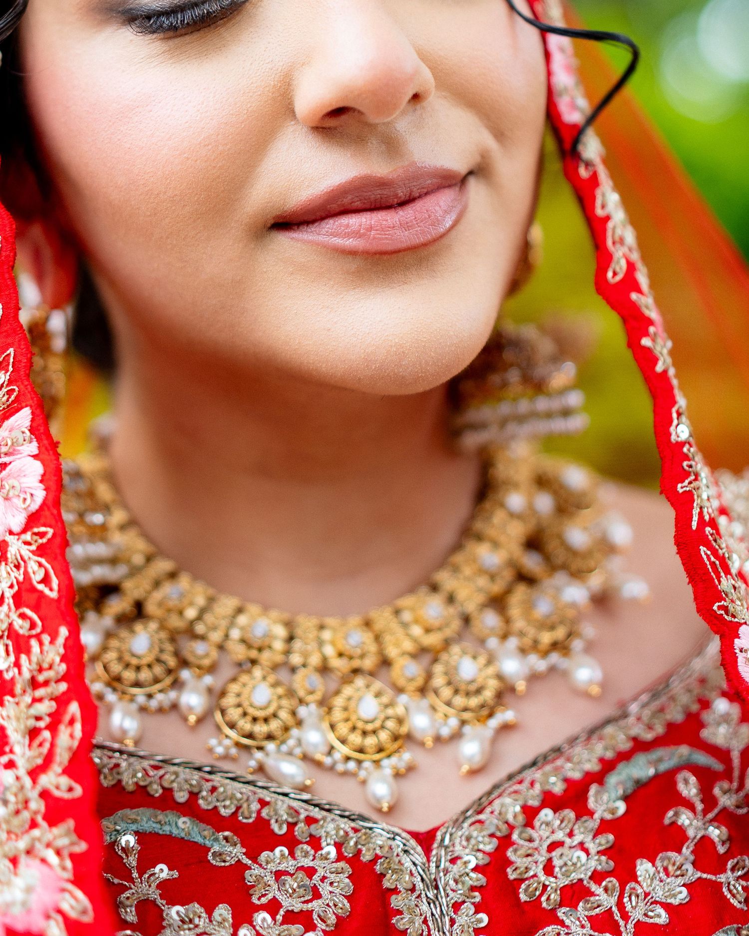 Close-up of Indian bride wearing ornate gold and pearl bridal necklace.