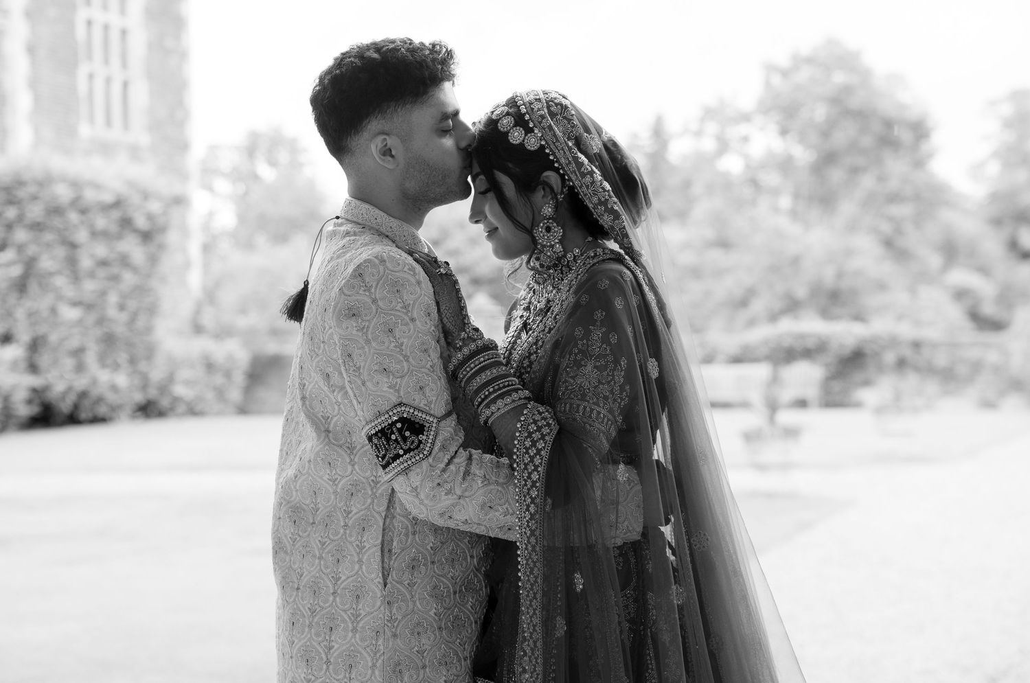Black and white romantic photo of South Asian wedding couple embracing outdoors.