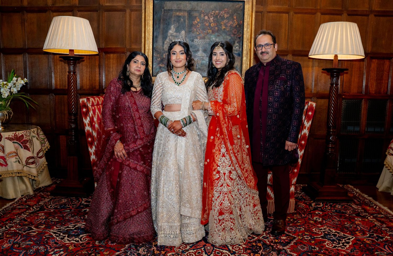 Indian family of four poses together in traditional attire inside an elegant manor house.