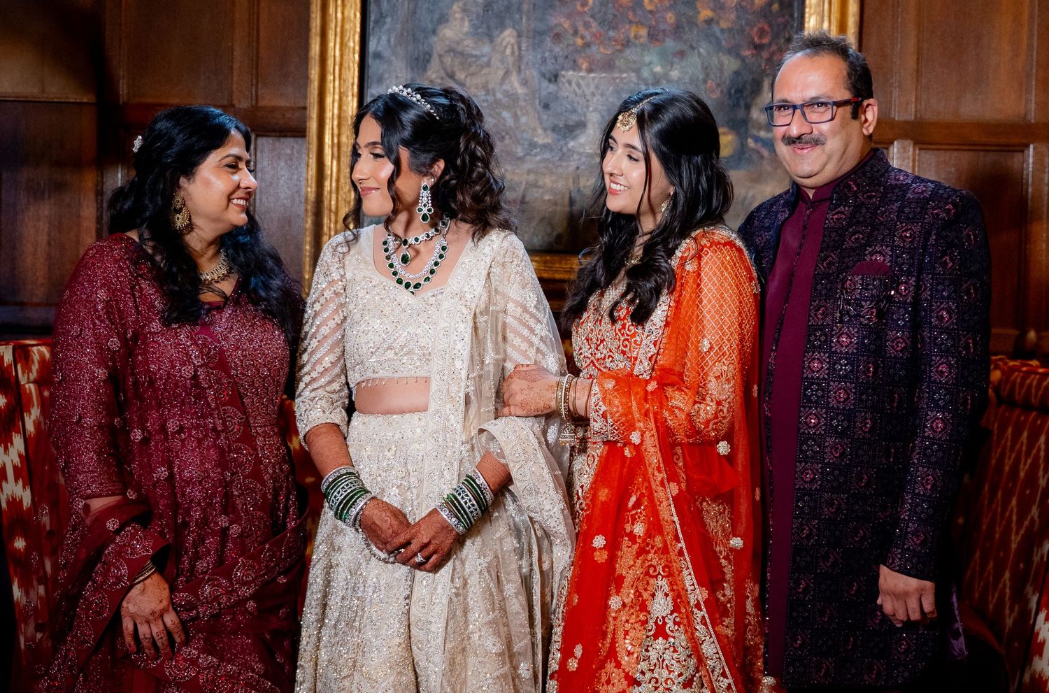 Four people in vibrant traditional Indian attire smiling together at a festive celebration.