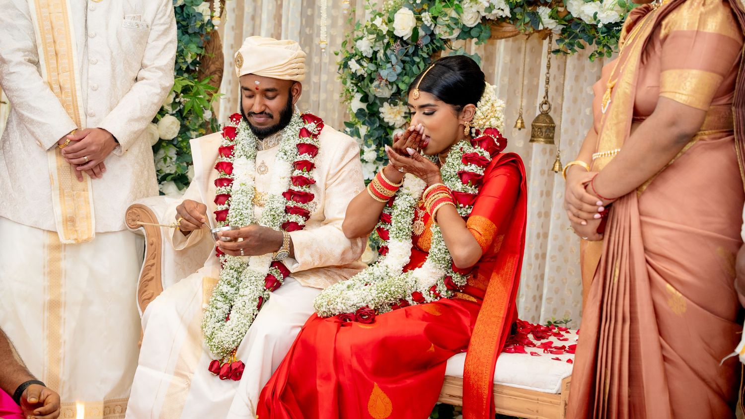 Bride and groom hold ceremonial items during a vibrant South Indian Hindu wedding ritual on the mandap.
