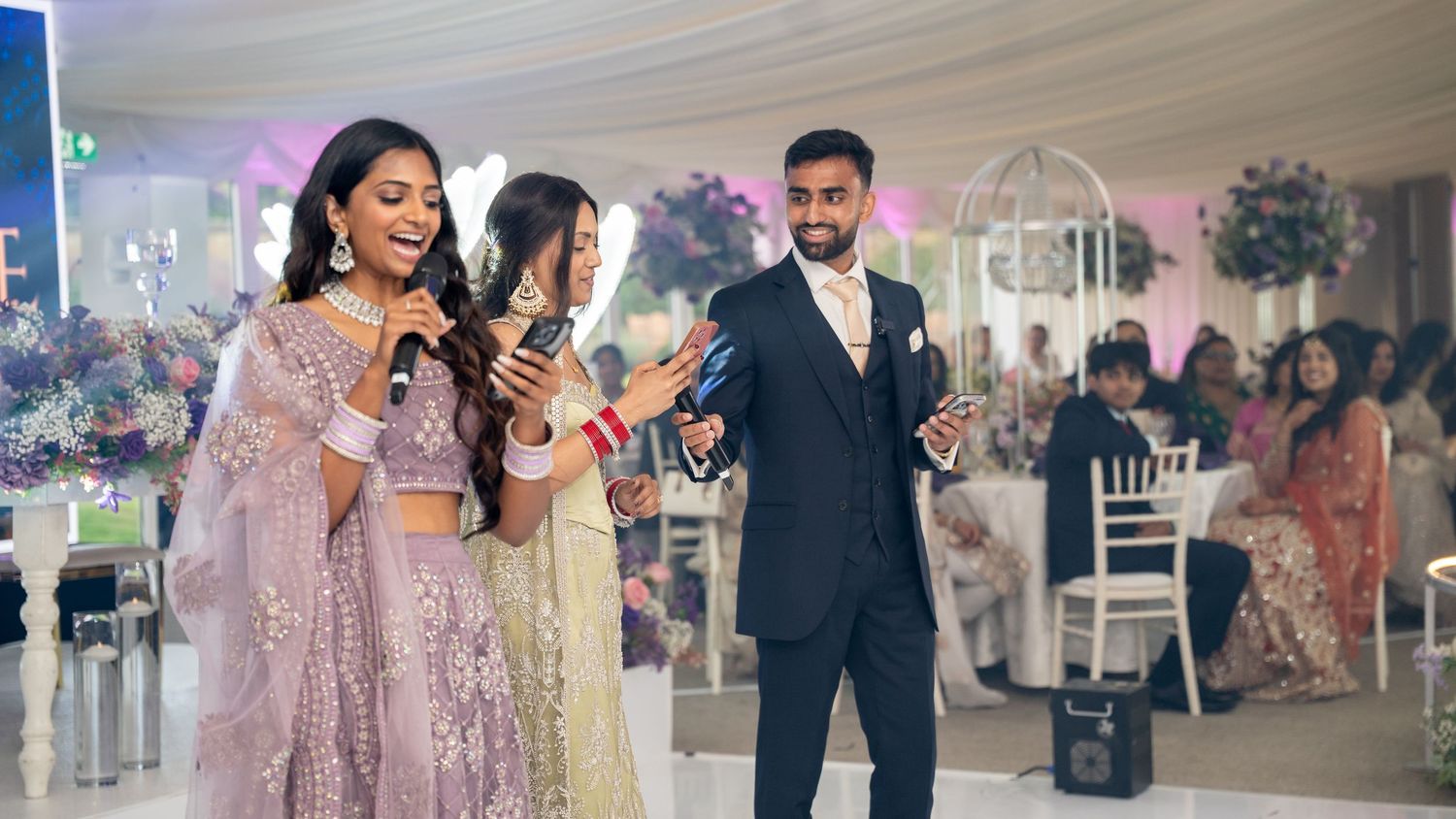 Indian wedding reception with bride, groom, and guests celebrating in elegant decorated venue.