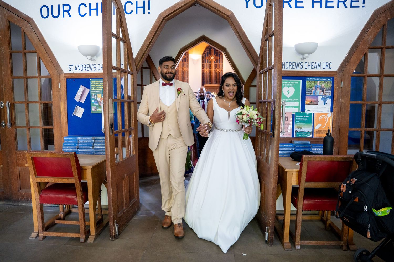 Bride and groom smile as they exit St. Andrews Cheam church together after their wedding ceremony.