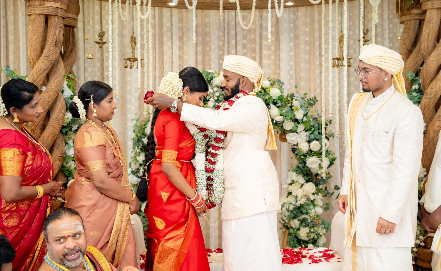 Bride and groom exchange garlands during a traditional South Indian Hindu wedding ceremony on a decorated mandap.