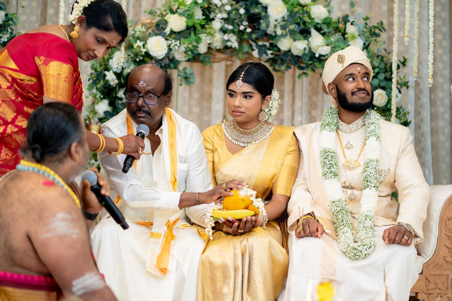 Traditional Tamil wedding with bride and groom seated at decorated mandap during religious ceremony.