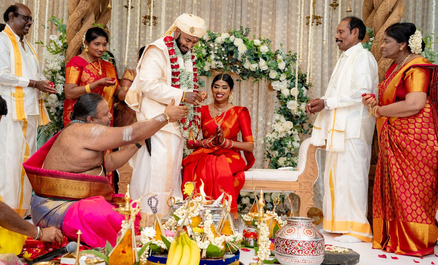 Traditional Hindu wedding with garland exchange ritual as family members witness the sacred ceremony.