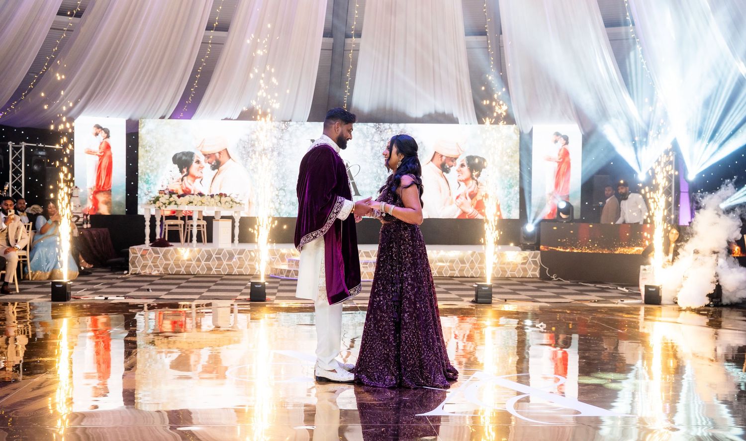 South Asian bride and groom sharing a romantic first dance on a reflective dance floor at wedding reception.
