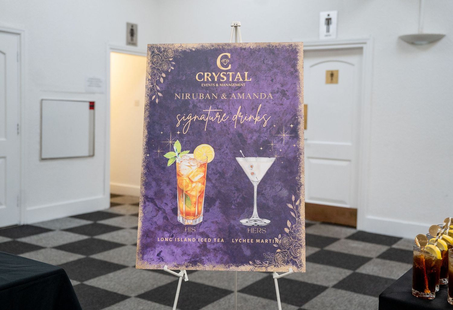 Crystal signature drinks wedding sign for Niruban and Amanda displayed on an easel with cocktail illustrations.