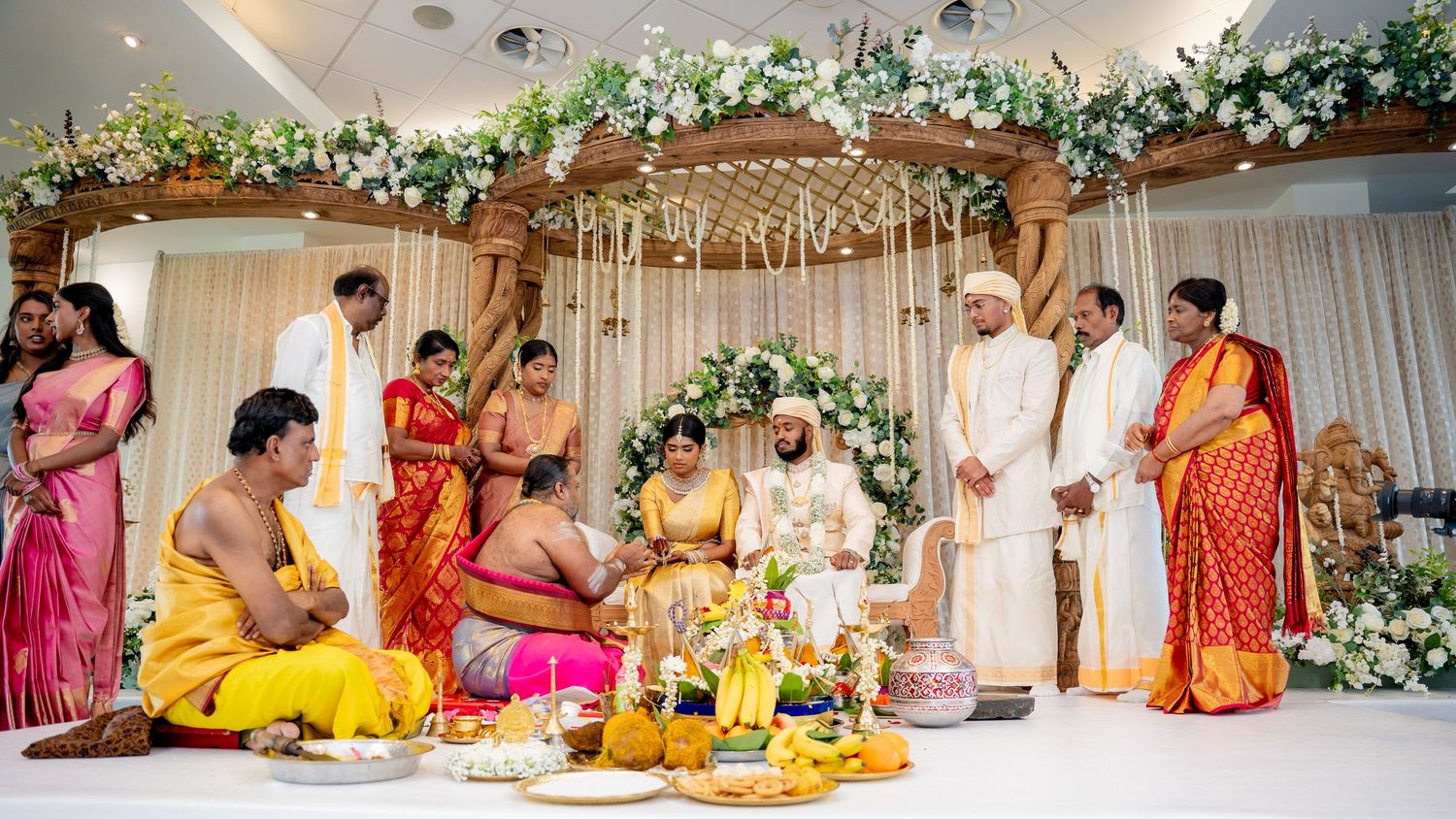Traditional Indian wedding ceremony with bride and groom performing rituals surrounded by family members in traditional attire.