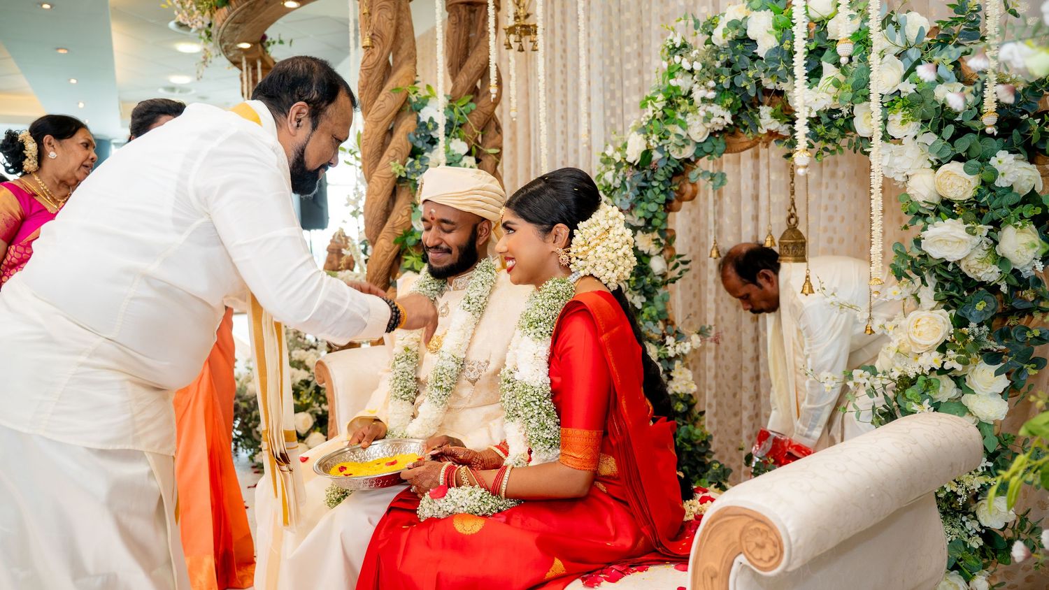 Elder man offering blessings to Hindu bride and groom during traditional Indian wedding ceremony celebration.