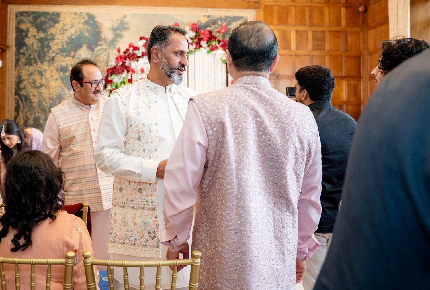 Men in traditional Indian kurtas greeting each other at a wedding ceremony.