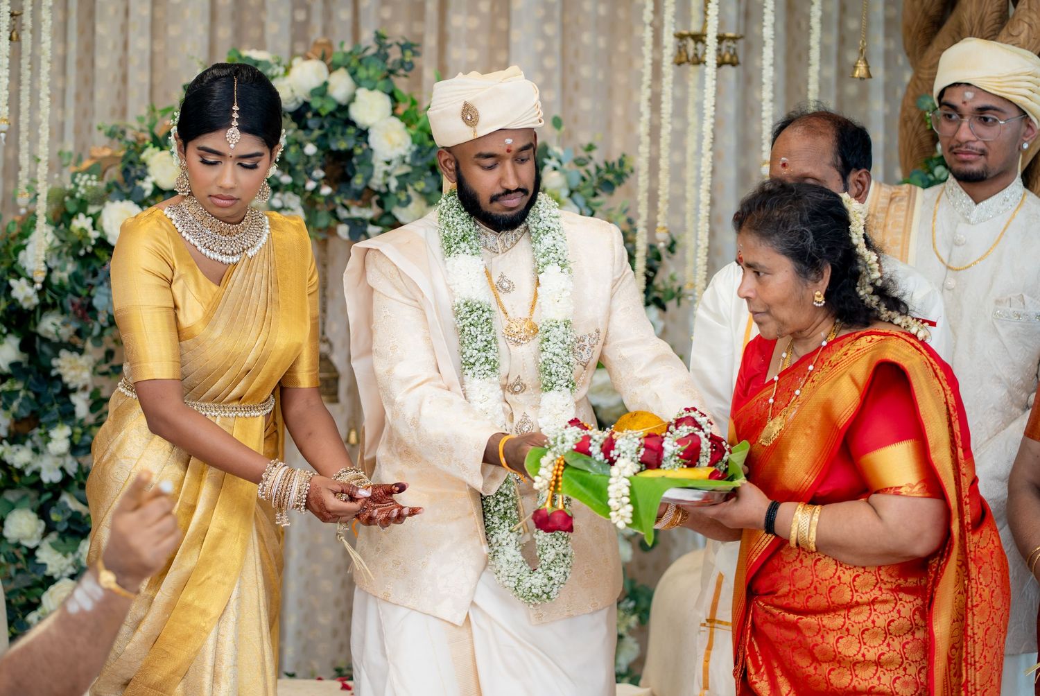 Traditional Indian wedding ceremony with bride and groom exchanging garlands surrounded by family members in colorful attire.