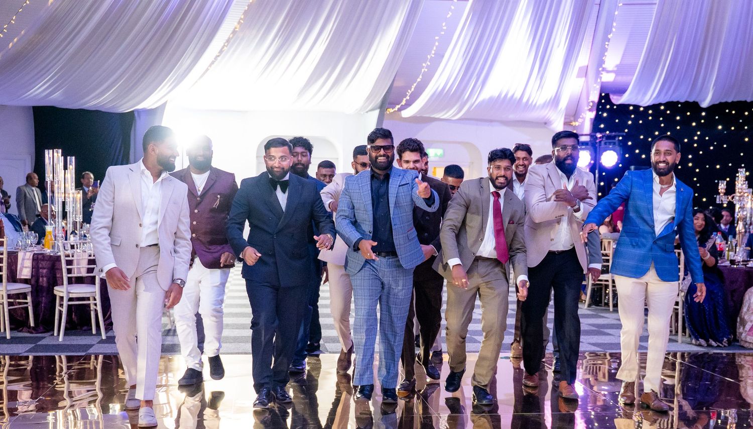 Stylish group of men in suits making a grand entrance on a shiny wedding dance floor.