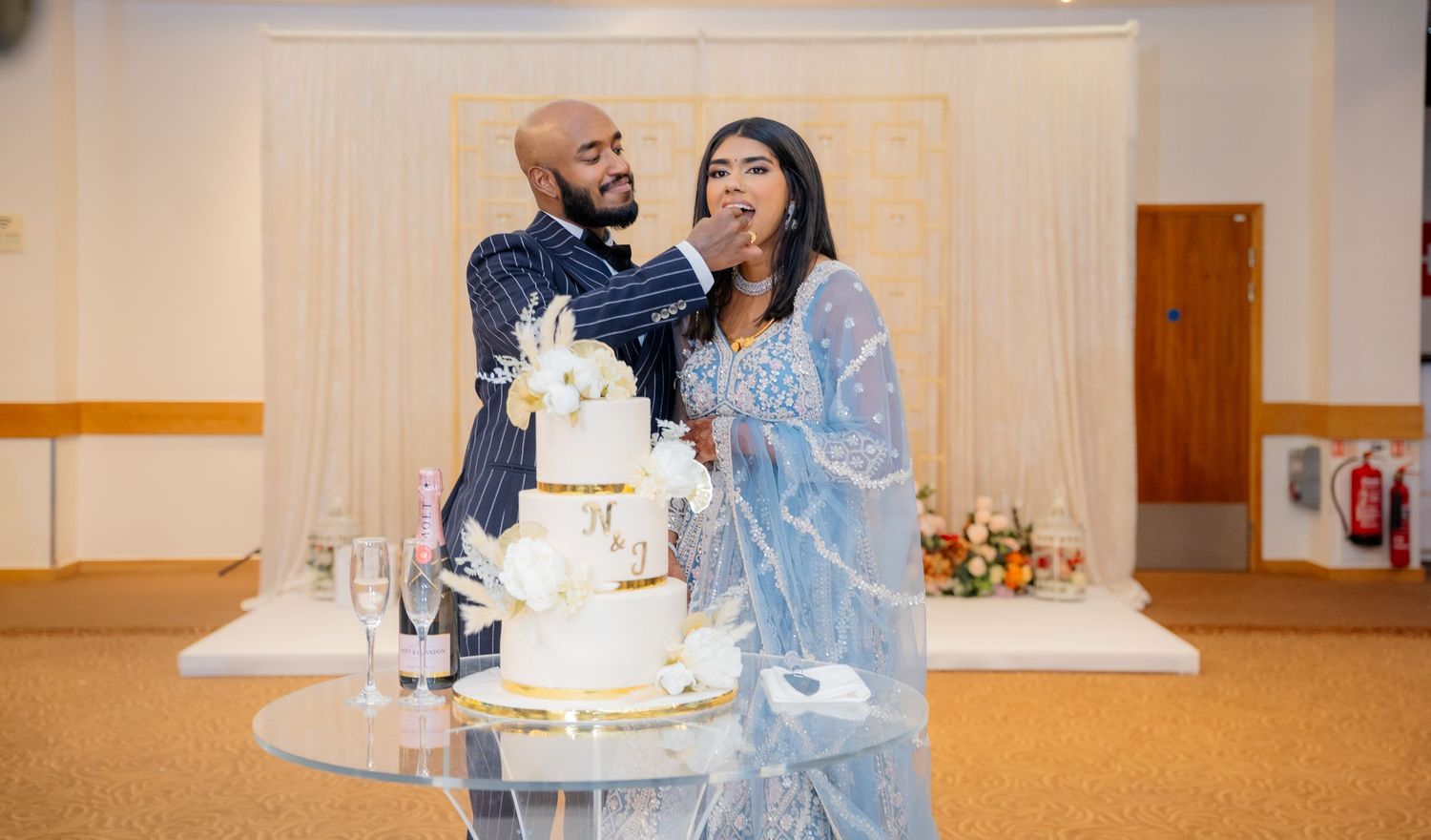 Bride and groom cutting their elegant white and gold wedding cake at a wedding reception.