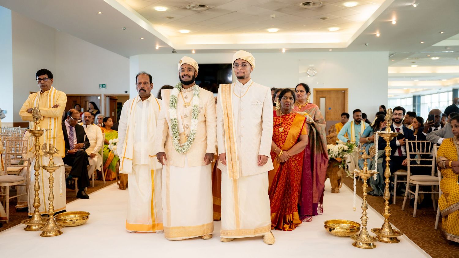 Two grooms standing at the altar during a traditional South Indian wedding ceremony.