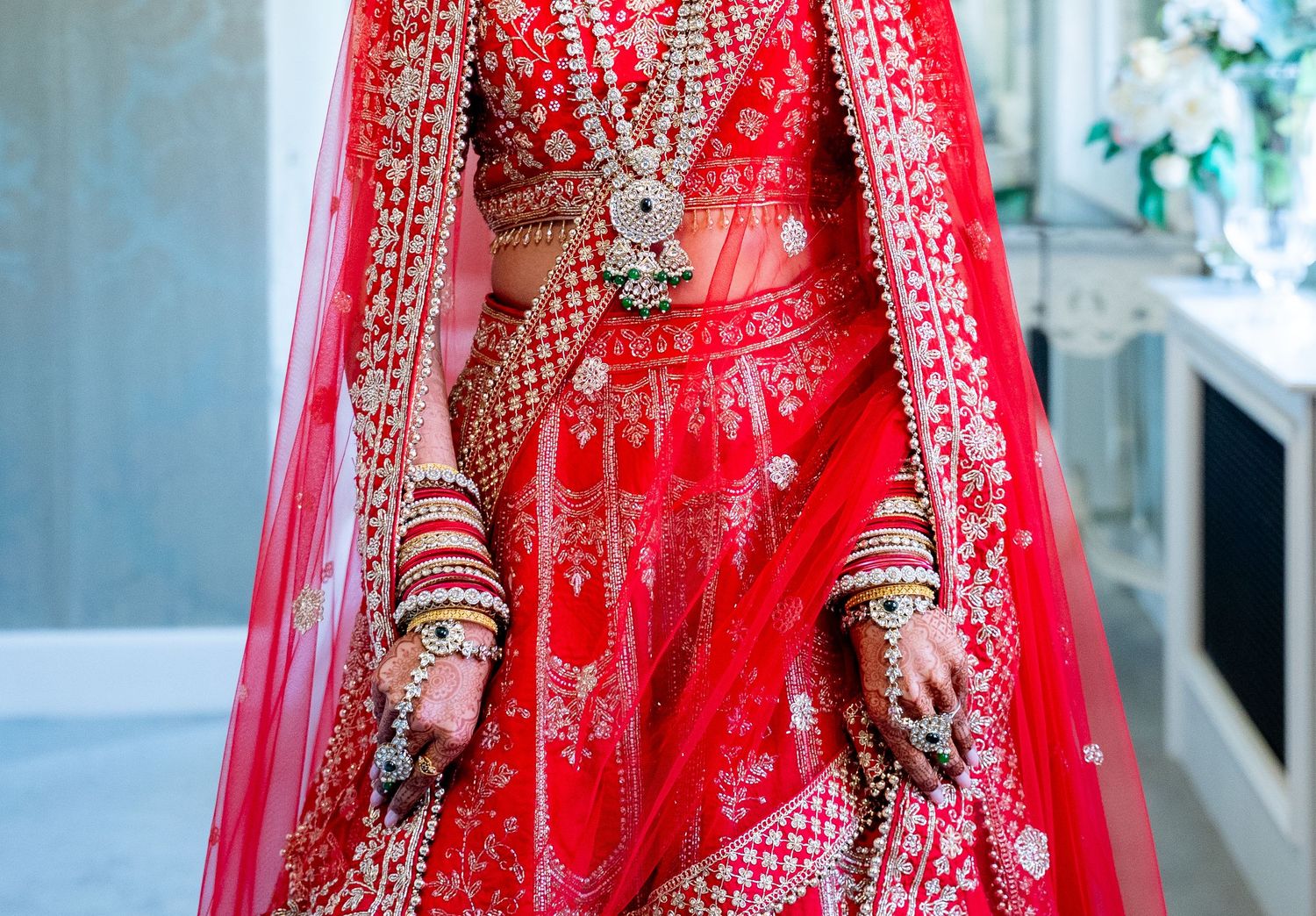 Close-up of red embroidered Indian bridal lehenga with intricate gold detailing.