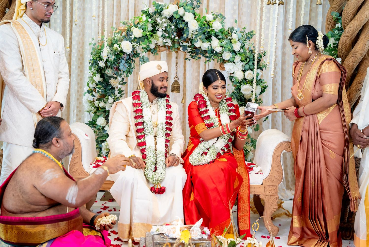 Priest leads sacred rituals as bride and groom sit together at traditional South Indian wedding.
