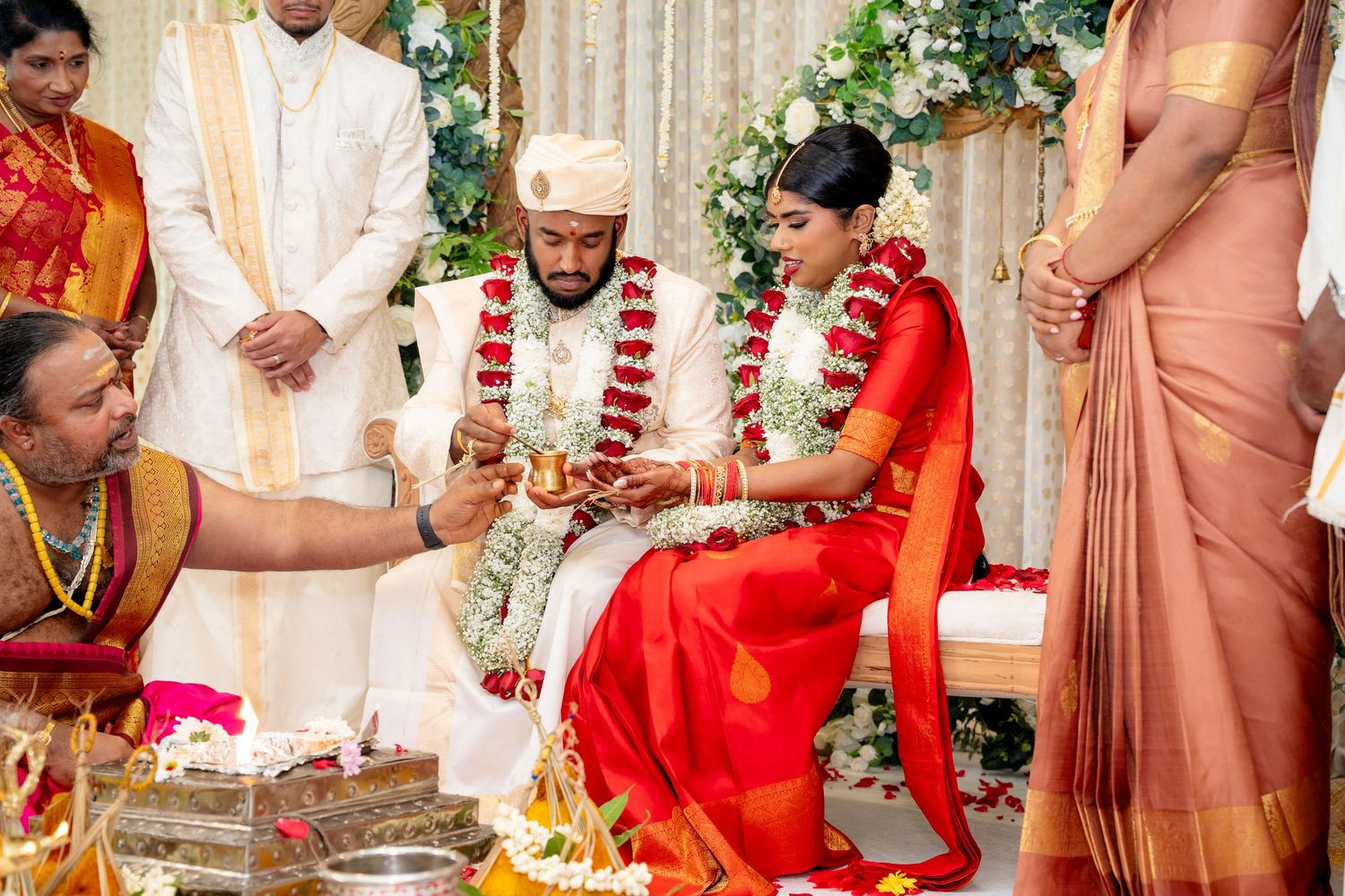 Priest performs sacred rituals as bride and groom participate in traditional South Indian wedding ceremony.