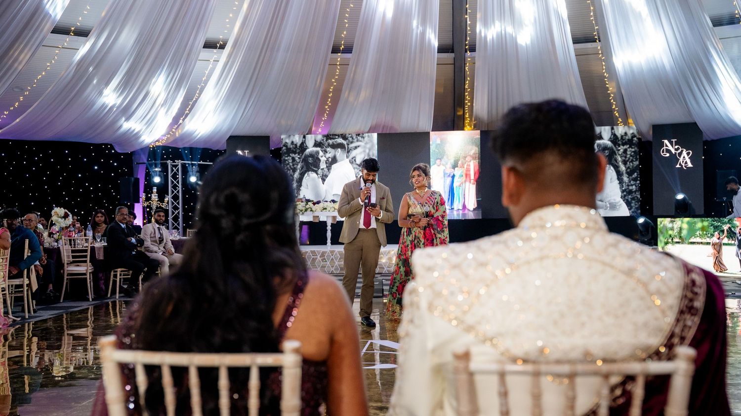 Wedding guests watching performers on dance floor at a beautifully decorated Indian wedding reception.