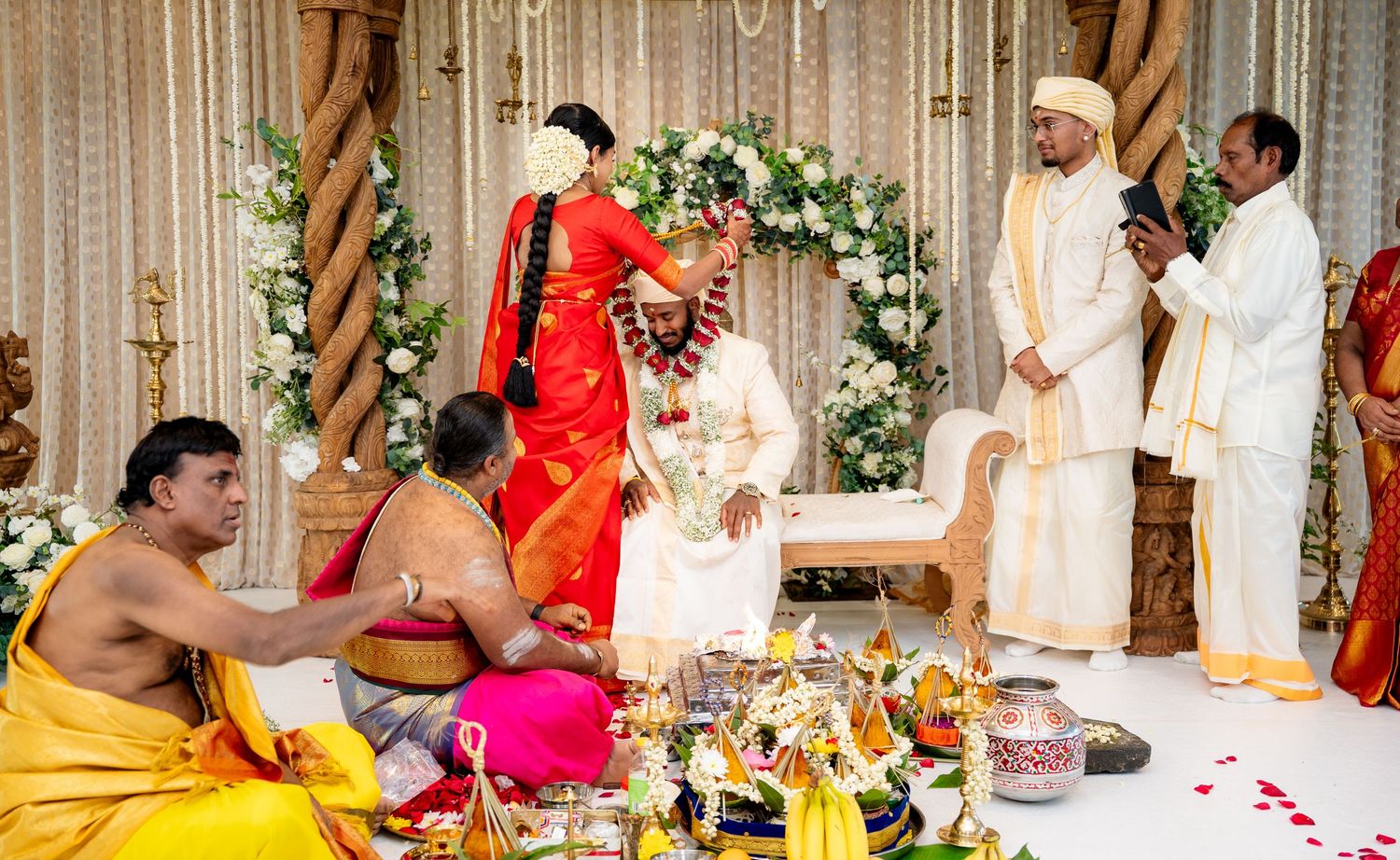 South Indian bride and groom exchange garlands at traditional Hindu wedding ceremony with priests.