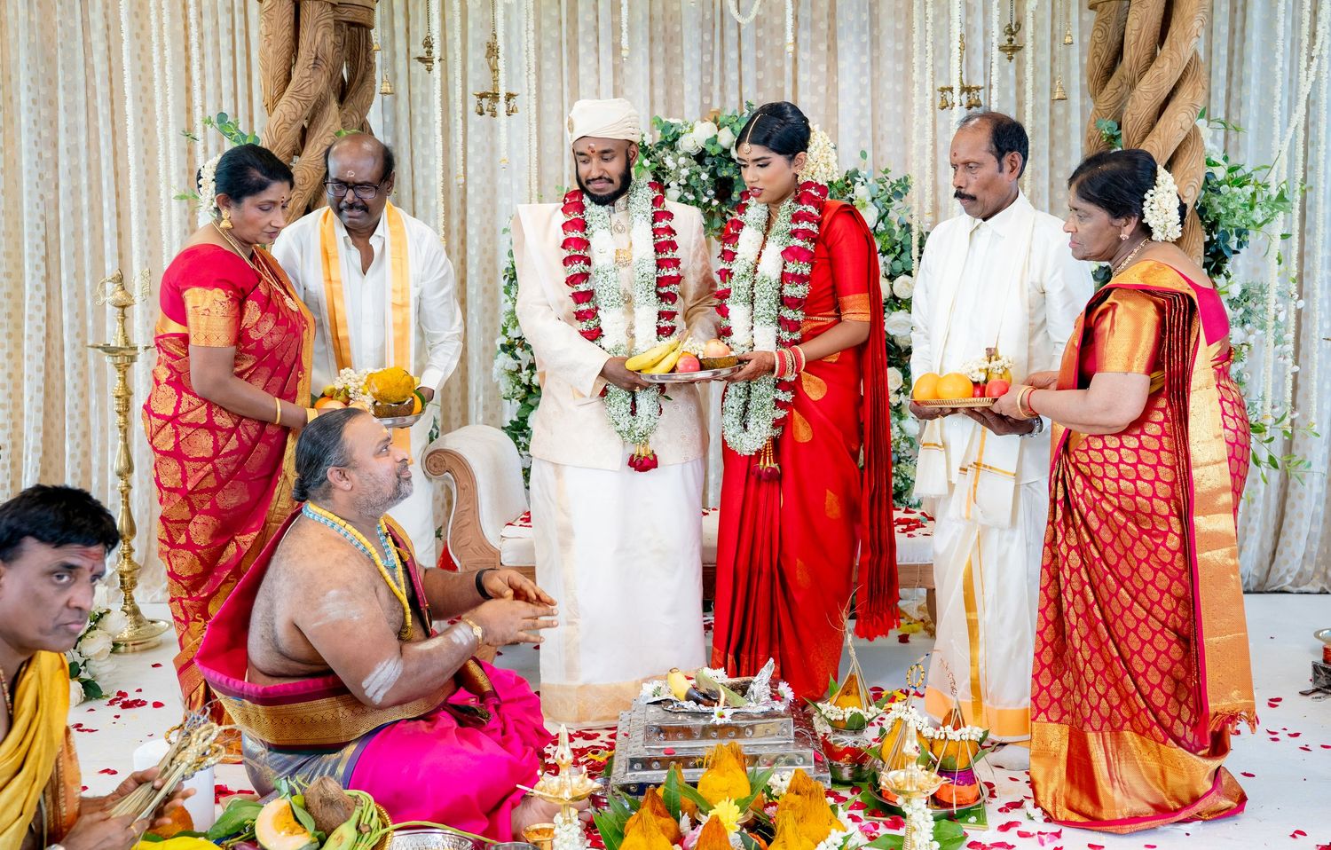Traditional South Indian wedding ritual with family members holding oil lamps blessing the bride and groom on mandap.