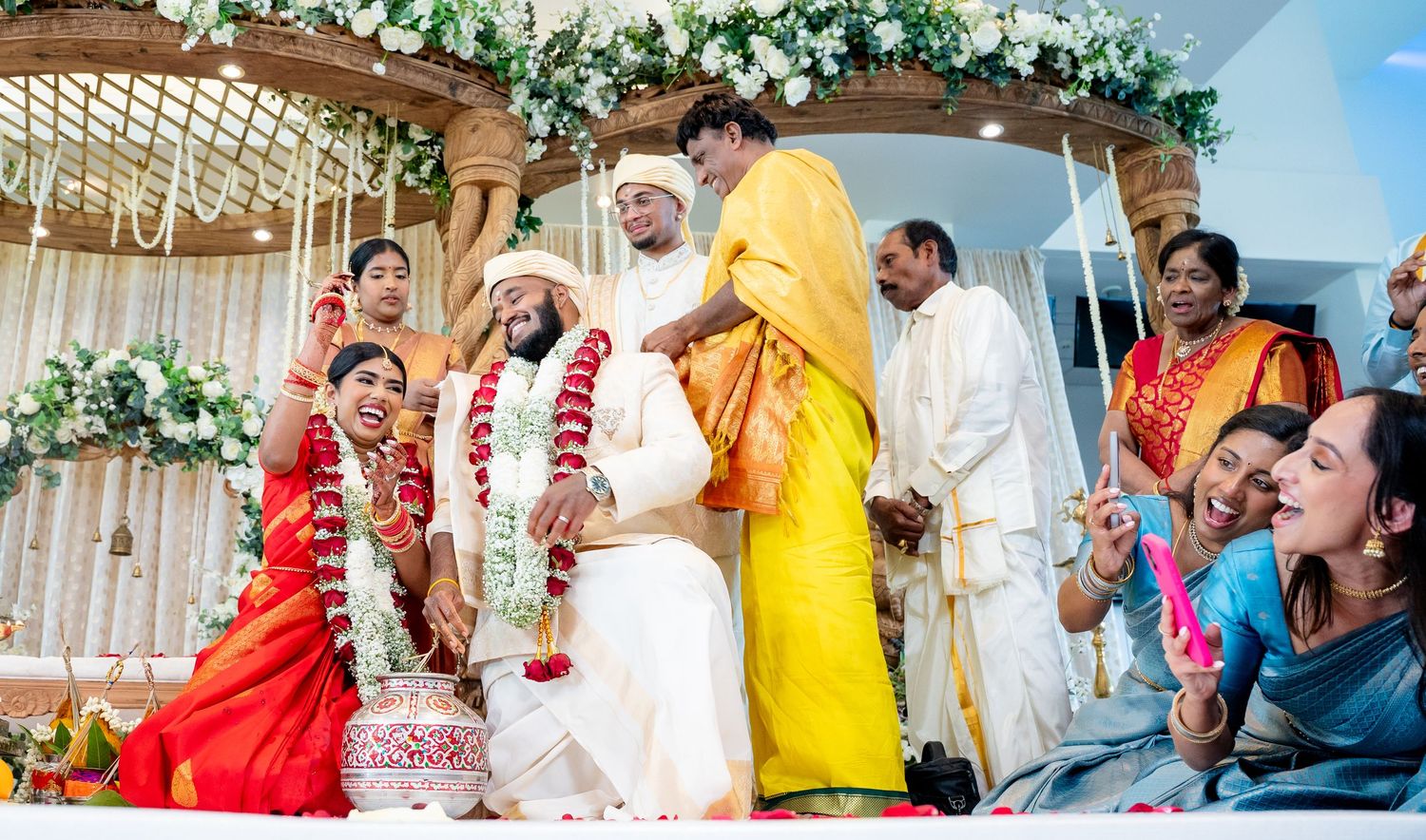 Joyful Hindu wedding ceremony with bride, groom, and family gathered under floral mandap.