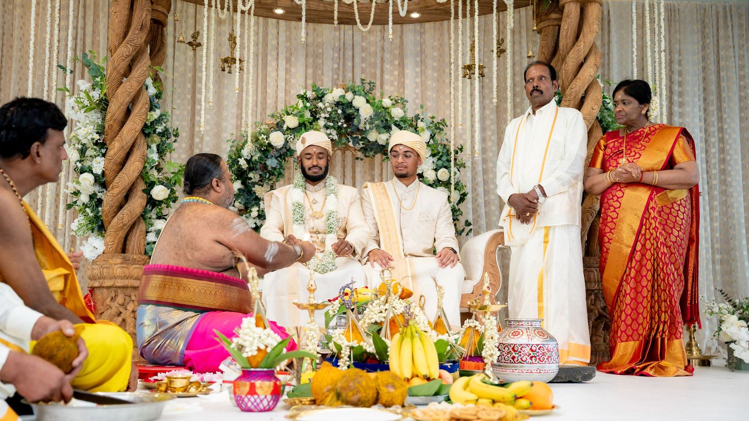 Groom and guests participate in traditional Hindu wedding ceremonies at an elegantly decorated mandap.