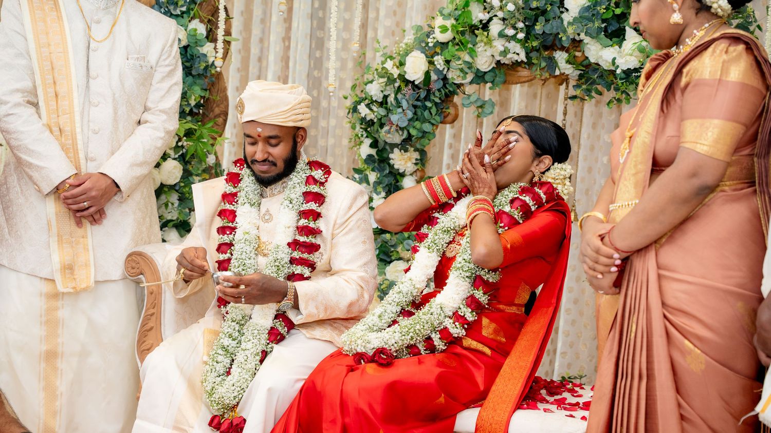 Bride wipes tears during heartfelt South Indian wedding ceremony while groom sits beside her on mandap.