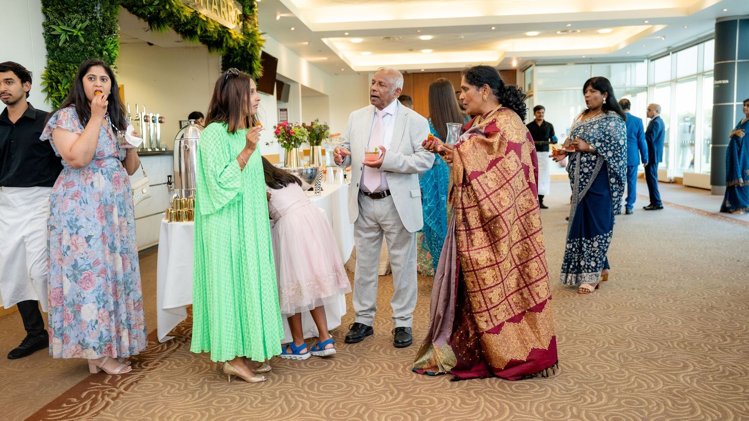 Guests in traditional and formal attire socializing at an elegant indoor celebration event.