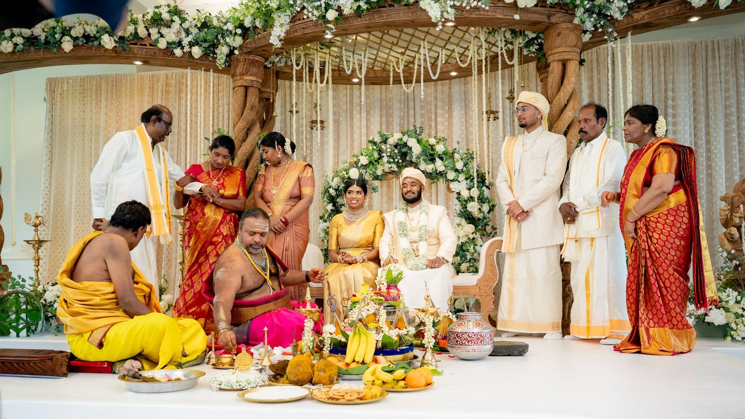 Traditional South Indian Hindu wedding ceremony with priests, bride in red saree, and guests gathered around ritual offerings.