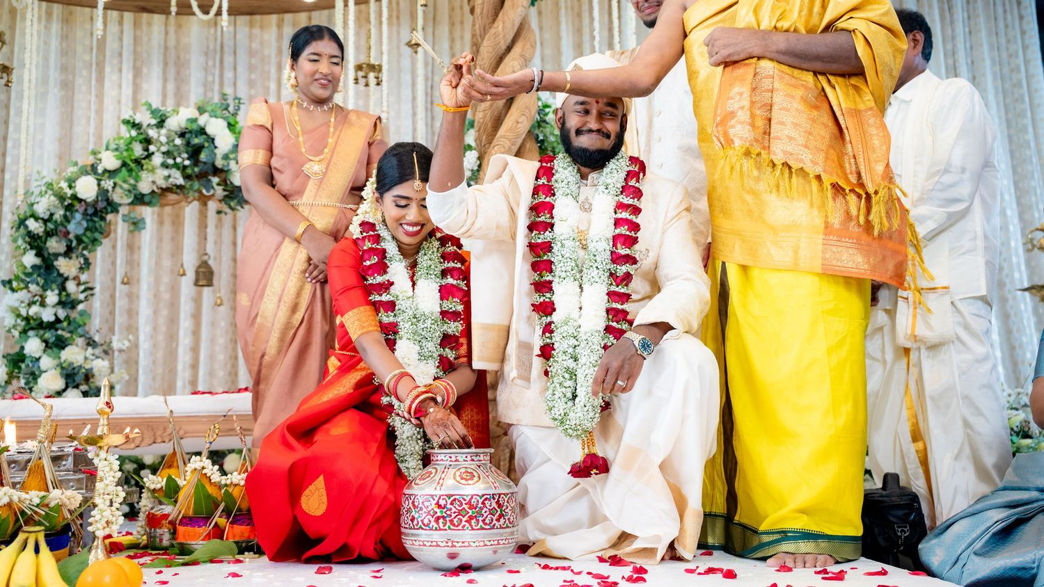 Traditional Hindu wedding ceremony with priest performing blessing ritual over decorated couple.