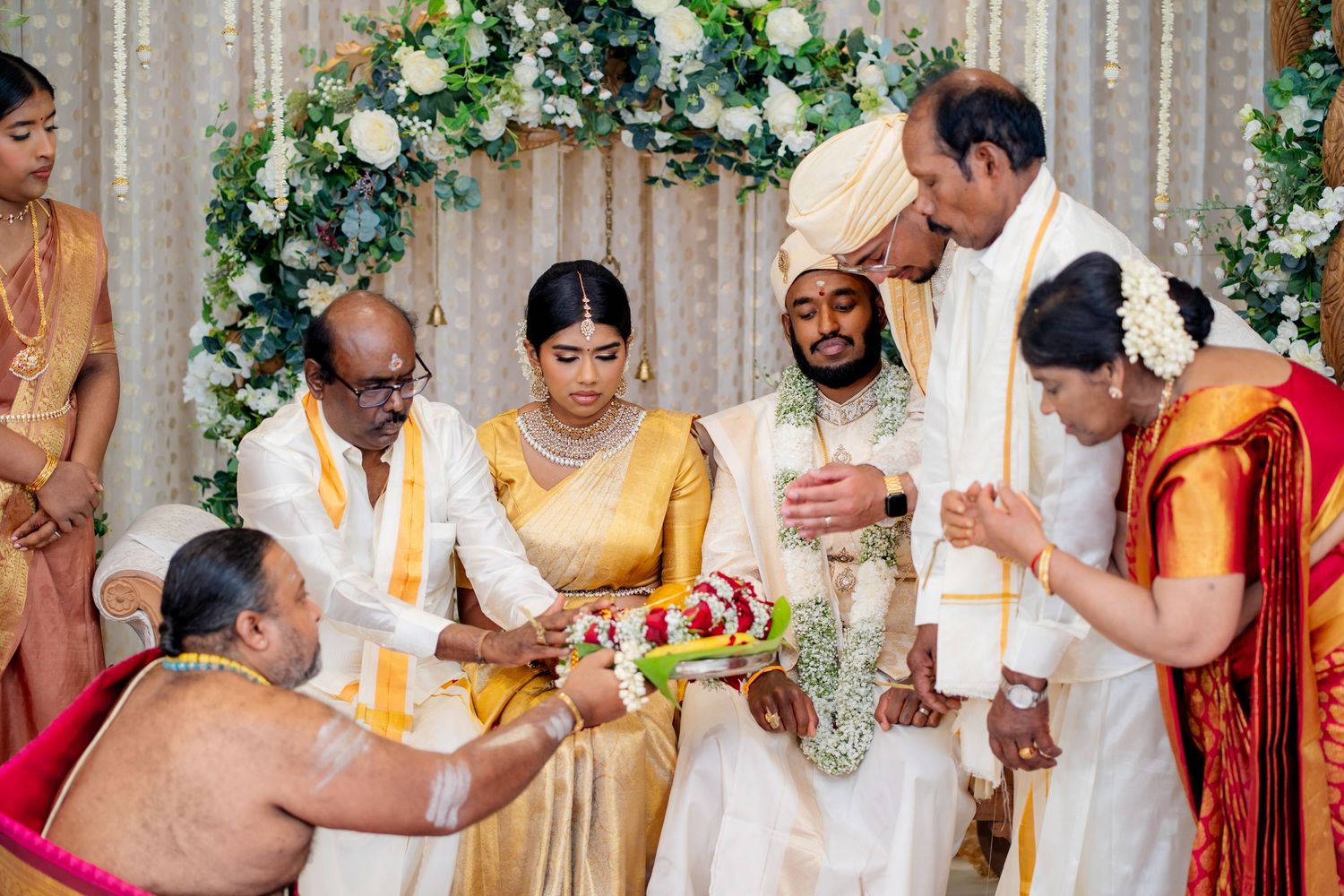 Traditional South Indian wedding ceremony with bride and groom in gold silk attire, surrounded by family during sacred rituals.