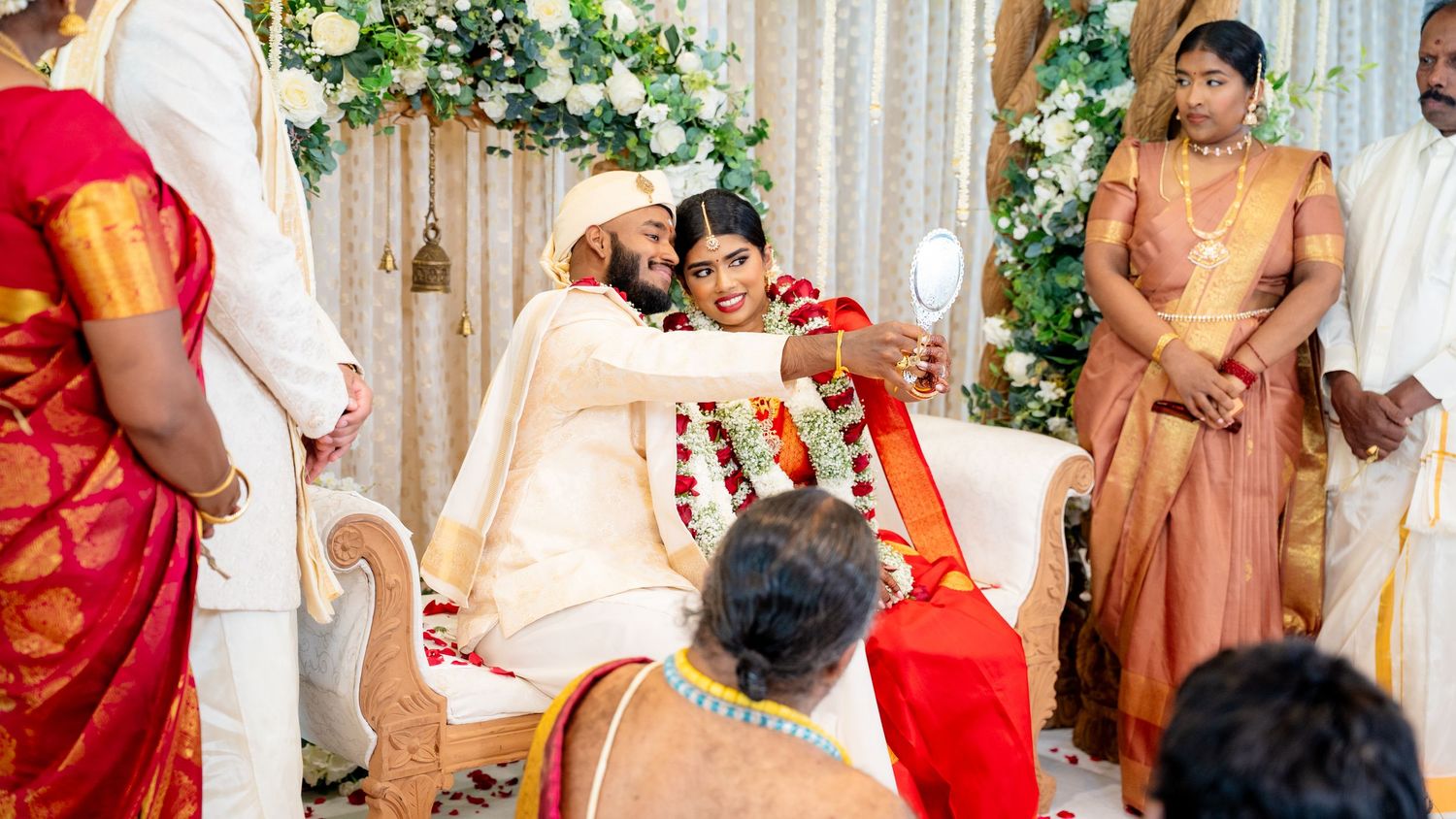 Groom applies sindoor to bride during sacred South Indian Hindu wedding ceremony with guests watching.