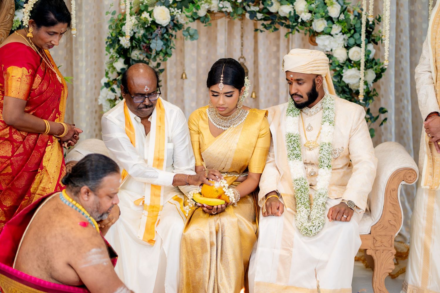 South Indian bride receives blessings during traditional wedding ritual with family members and priest at decorated mandap.