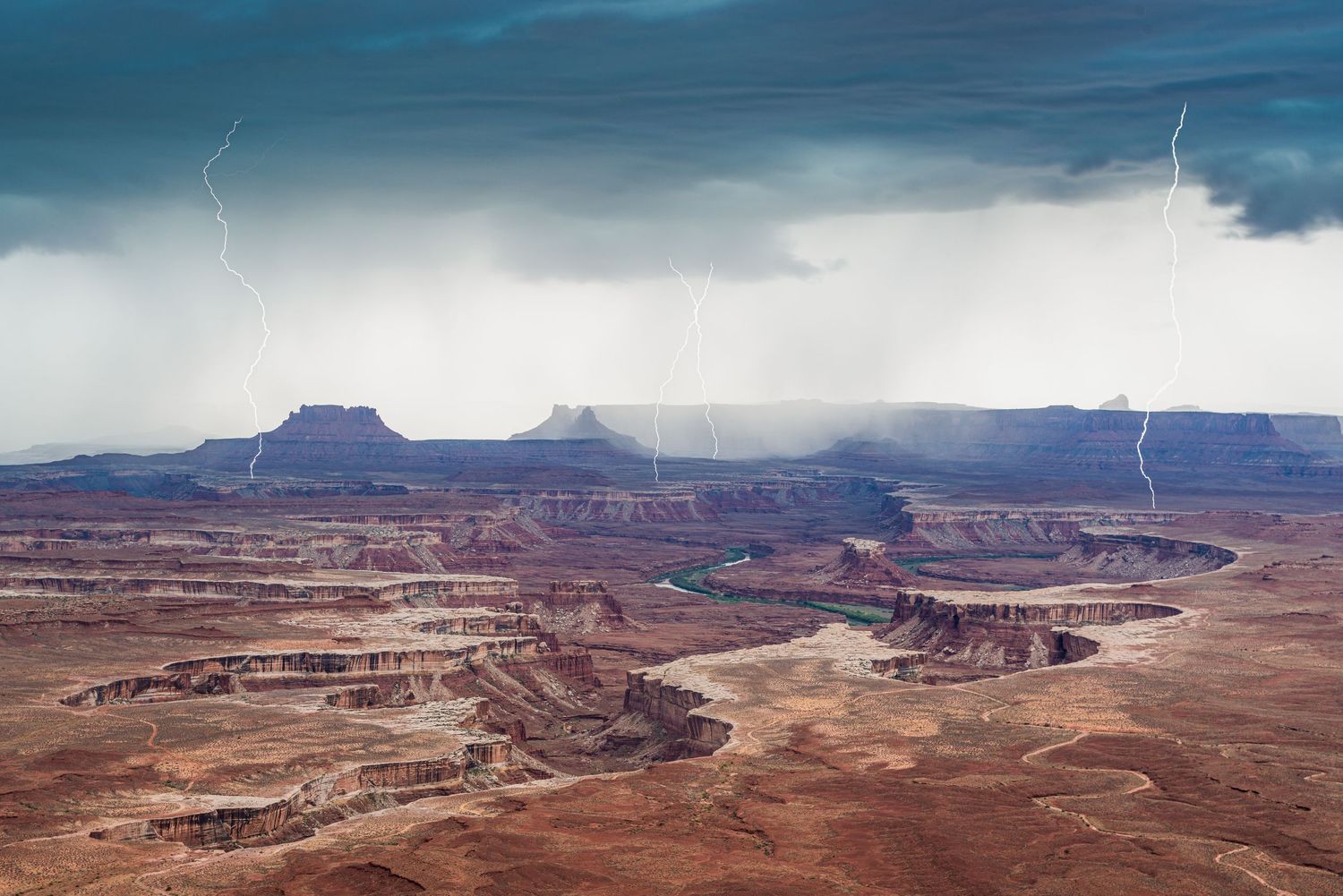 Dramatic lightning storm over the vast red rock canyons and winding river of Canyonlands National Park, Utah.