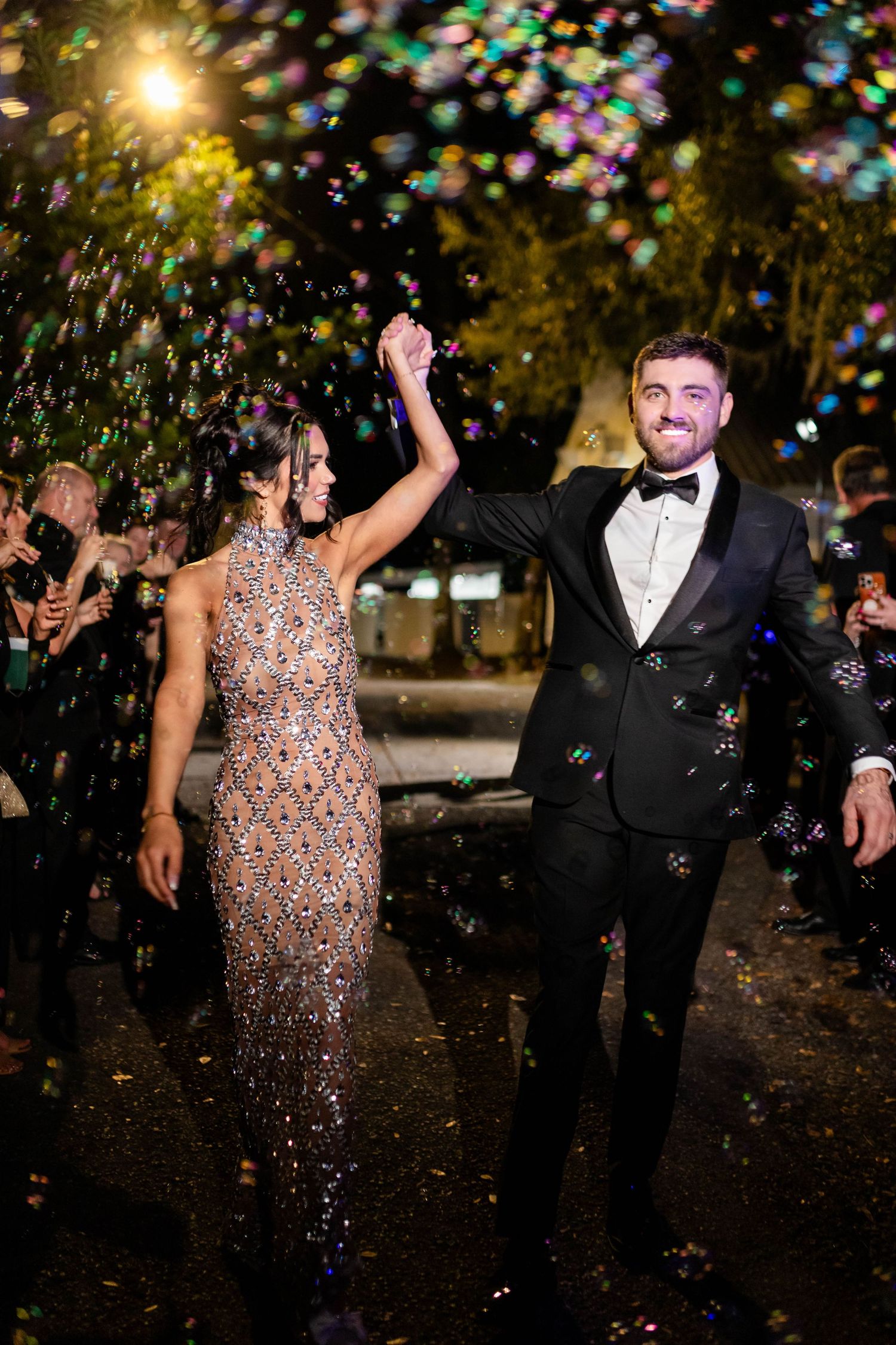Bride and groom celebrate their grand exit under a shower of colorful bubbles in Tampa at night.