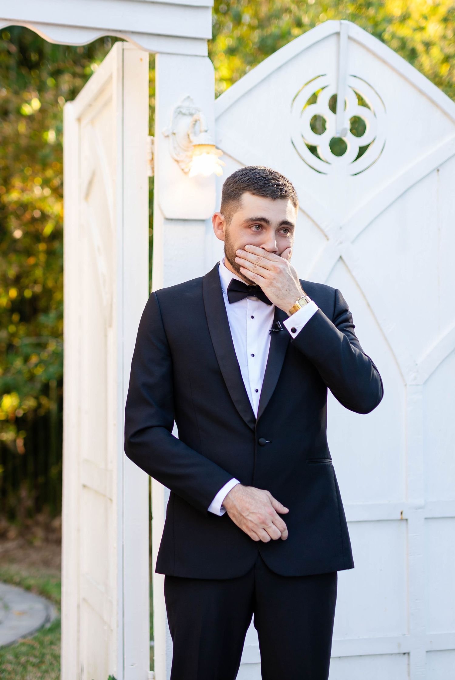 Emotional groom in black tuxedo covers his mouth in awe during the first look at his wedding in Tampa.