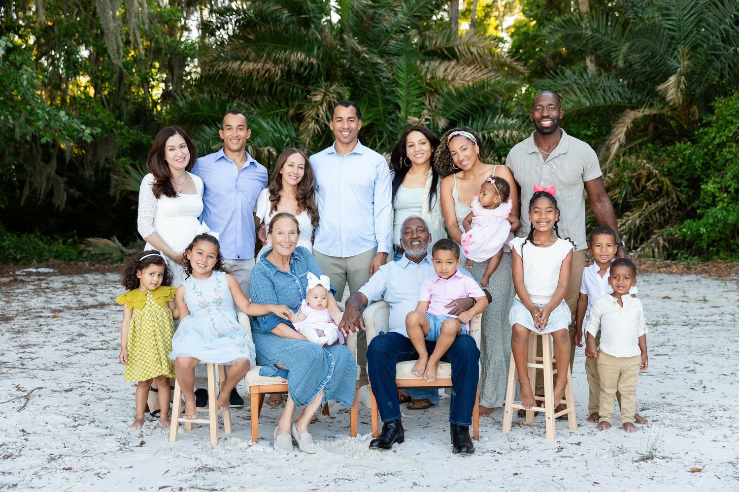 A large multigenerational family poses together on a sandy beach surrounded by lush greenery in Wesley Chapel.