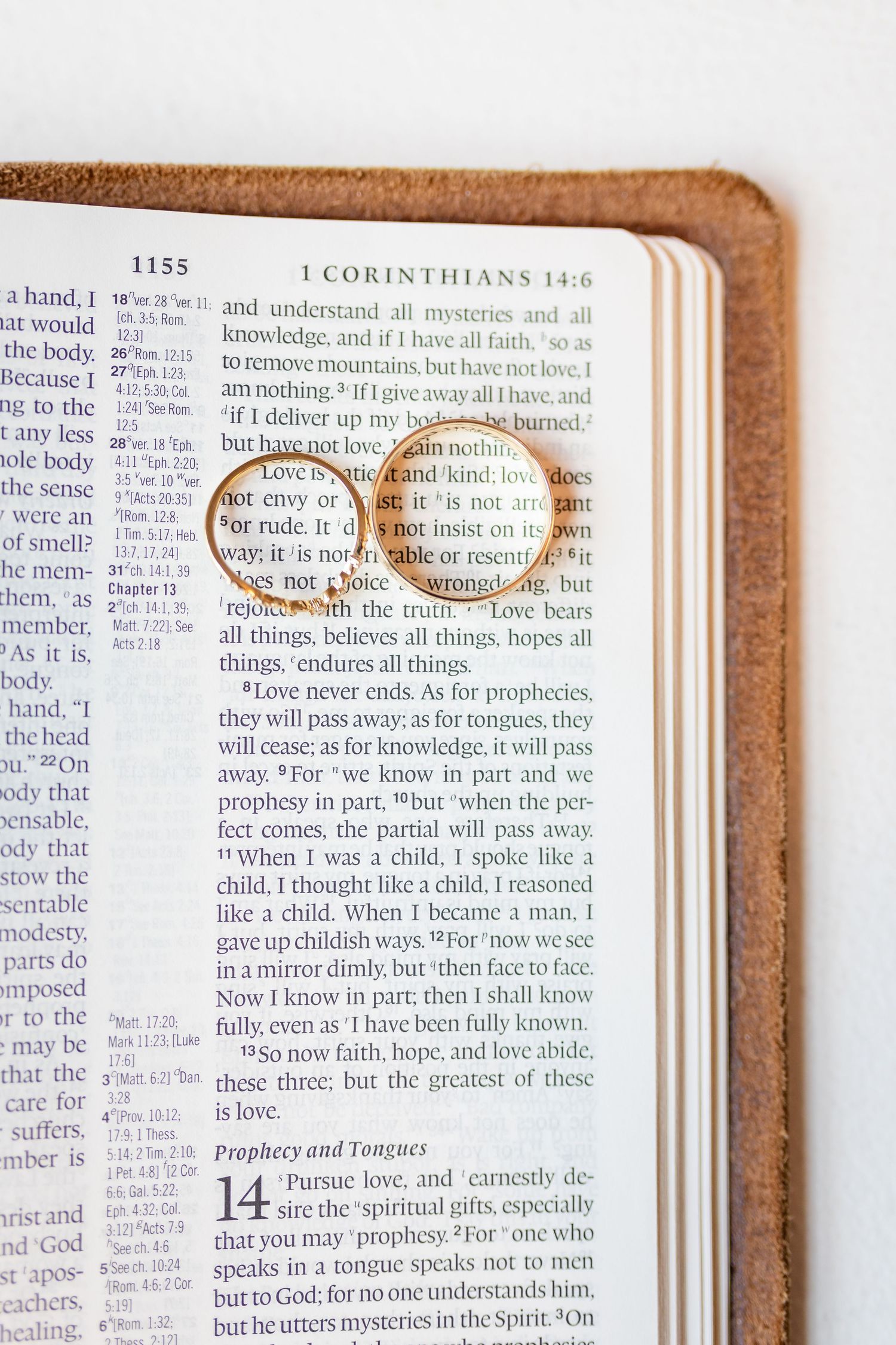 Open Bible displaying 1 Corinthians 13, a popular wedding scripture, with a gold ring resting on the page.