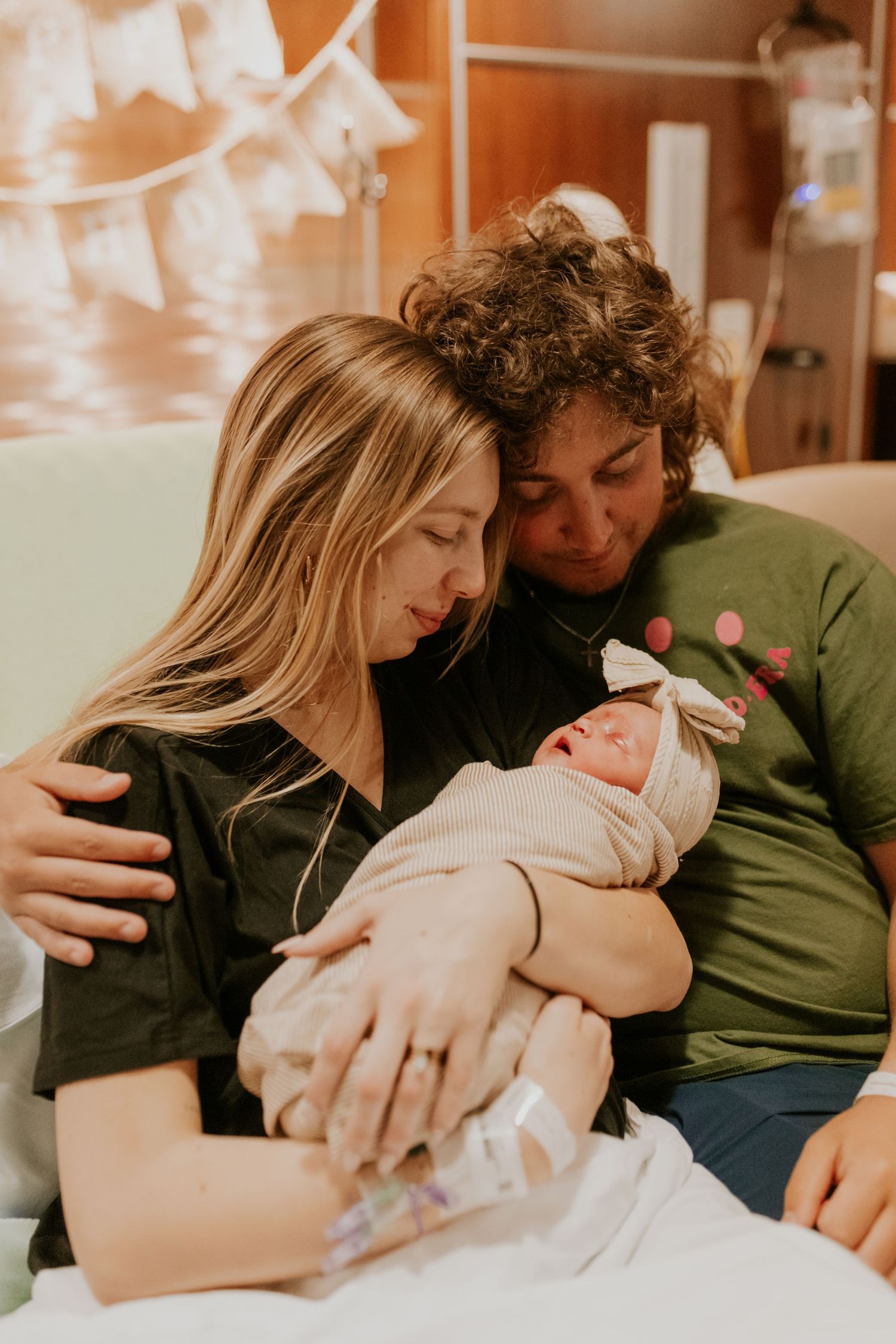 New parents tenderly hold their swaddled newborn together in a hospital room after birth.