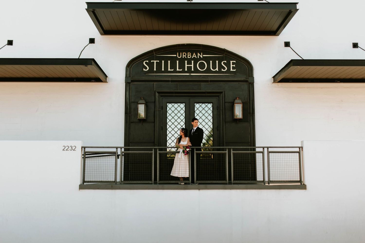 Wedding couple standing on balcony outside Urban Stillhouse venue entrance.