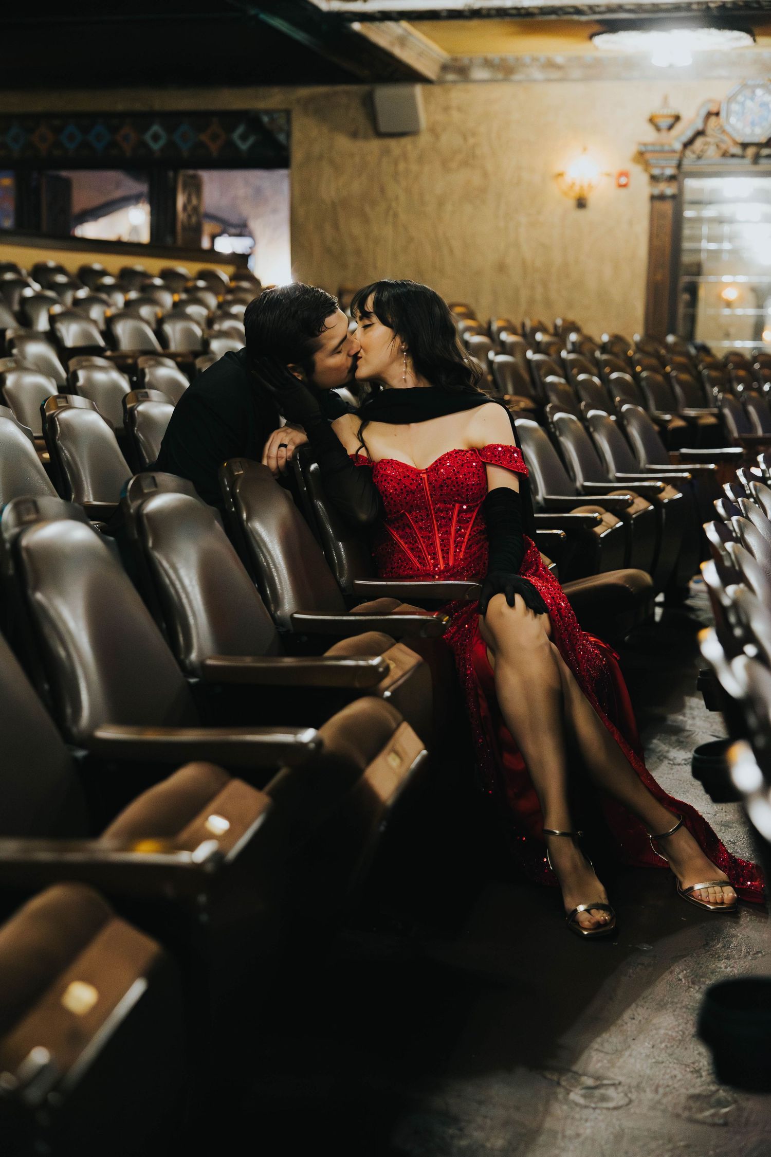 Couple sharing a romantic kiss in the aisle seats of a classic vintage Tampa theater.