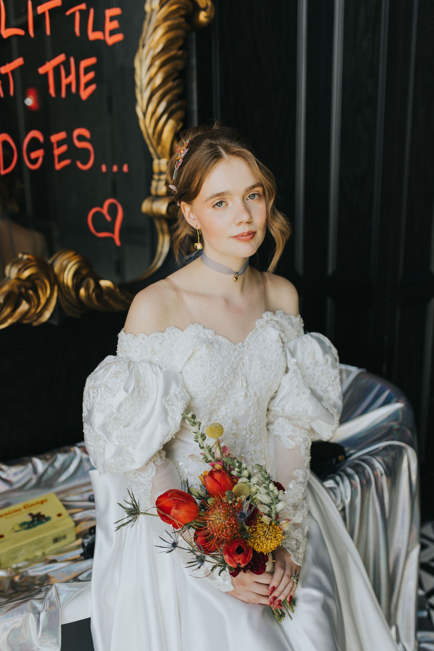 Elegant bride in off-shoulder lace gown holding colorful red and yellow bouquet indoors at The Floridian Social St. Petersburg, Florida.